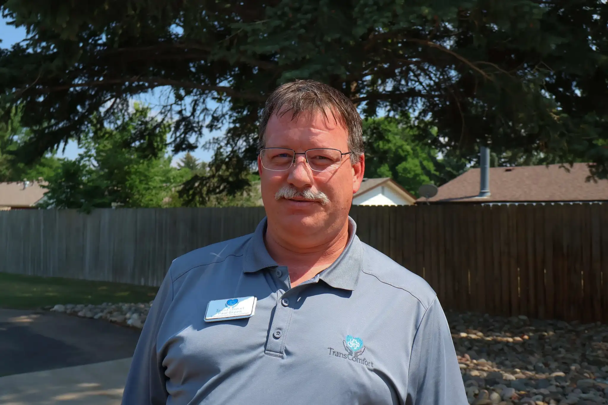 A TransComfort team member in a company polo shirt, photographed outdoors.